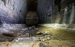 Zdjęcie przedstawiające wnętrze jednego z korytarzy w bunkrach, oświetlonego za pomocą latarki.